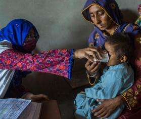 An MSF staff member treats a child carried by their mother in Pakistan after the floods.