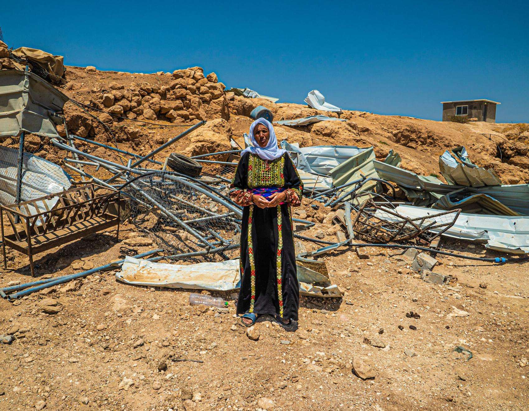 A woman stands before the rubble left of her home after it was demolished by Israeli forces in Masafer Yatta, West Bank.