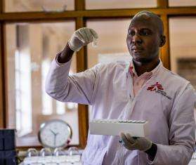 An MSF doctor holds up a test tube he is examining in a lab in Arua, Uganda.