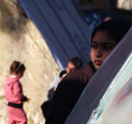 Displaced Palestinians by a tent in Rafah, Gaza.