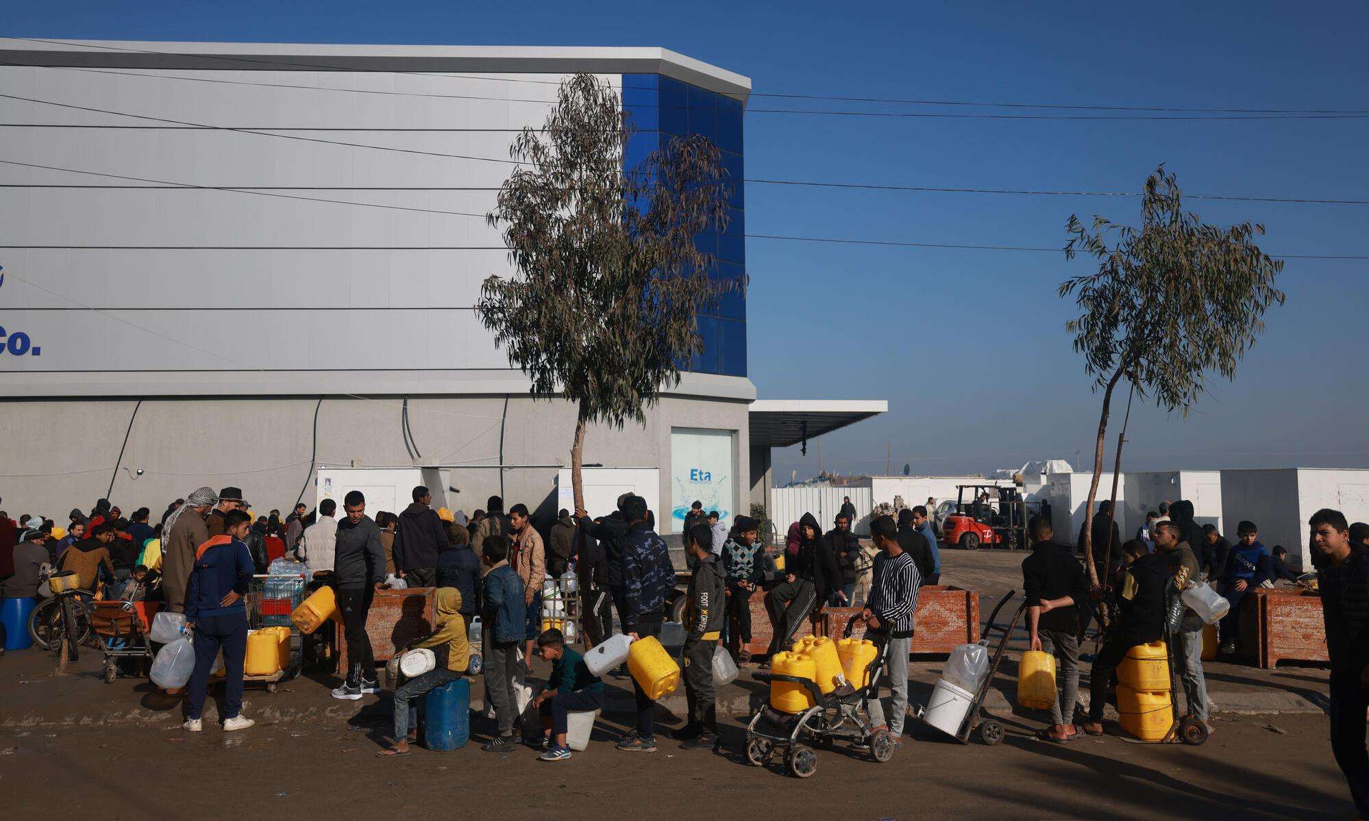 Displaced Palestinians wait in line to get the clean water from a water station in Tal Al-Sultan, a neighborhood in the southern Gaza town of Rafah.