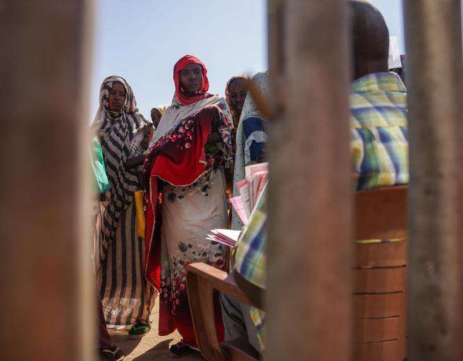 A woman waits in line at a feeding center in Zamzam camp, Sudan. 