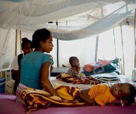 Mother sits beside her child receiving treatment for malaria.