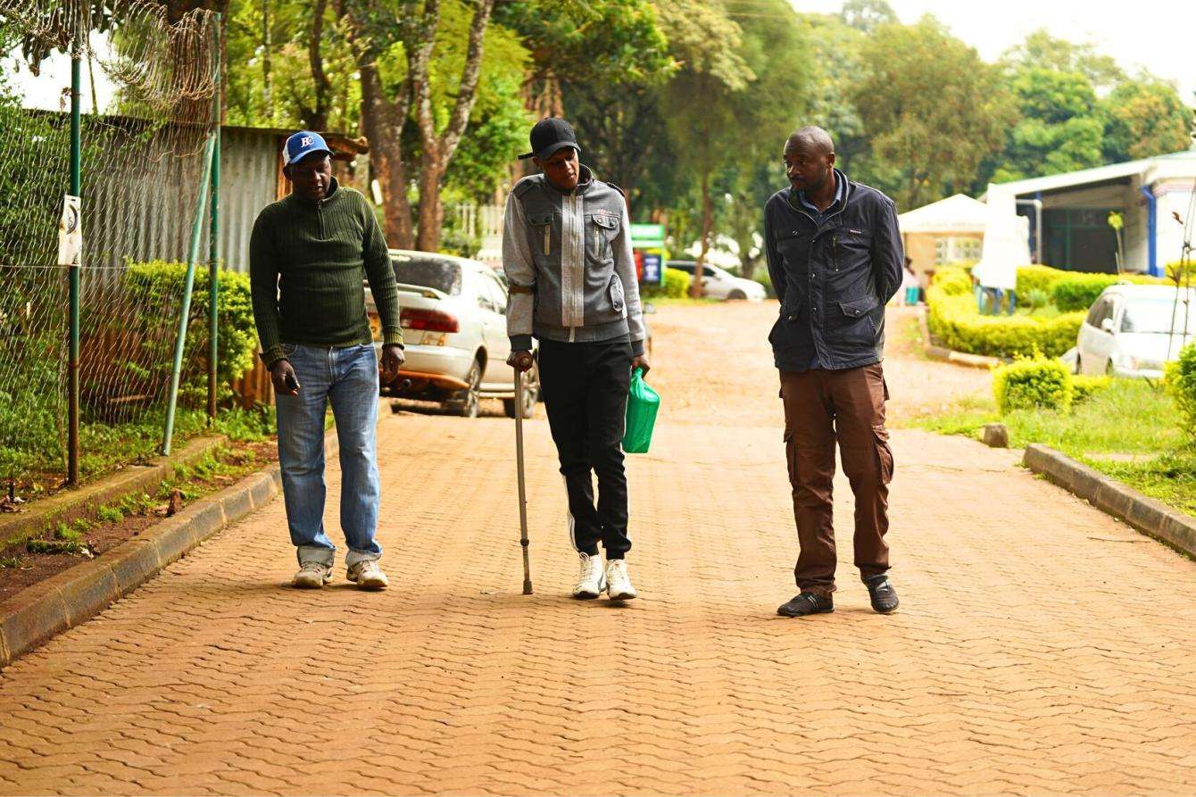 Mburu Michael is flanked by his father (left) and uncle (right) as they arrive at the Karuri medically assisted therapy clinic in Karuri for his take home methadone dose in Kenya.