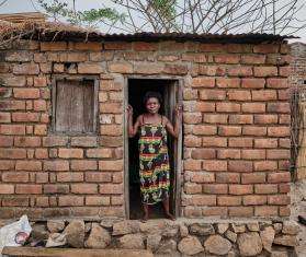 A woman standing in the doorway of her brick home in Malawi.